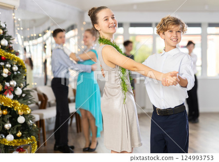 Couples dancing - teenagers in festive clothes dance the Viennese waltz near Christmas tree 124993753