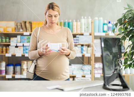Pregnant woman customer choosing pills in box in drugstore Pregnant woman customer choosing pills in box in drugstore 124993768