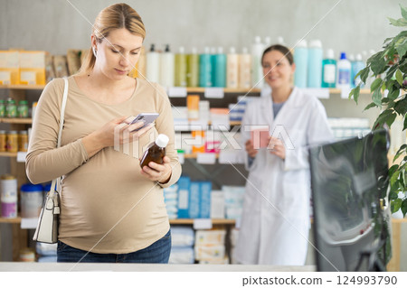 Pregnant woman in pharmacy scan QR code on syrup, pharmacist offer similar product in background Pregnant woman in pharmacy scan QR code on syrup, pharmacist offer similar product in background 124993790