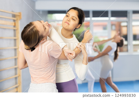 Asian woman practicing arm hold with elbow strike to chin in self-defense training 124993830