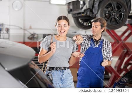 Male mechanic giving car keys to woman client 124993894