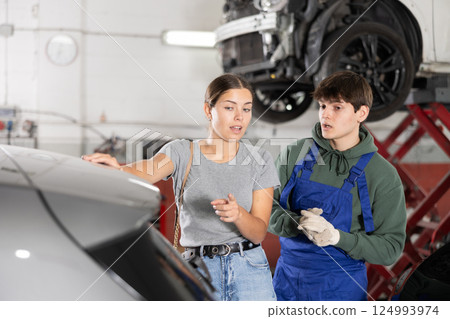 Guy car repair shop worker consulting woman client 124993974