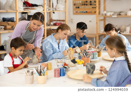 Children sit at the table and paint ceramics Children sit at the table and paint ceramics 124994039