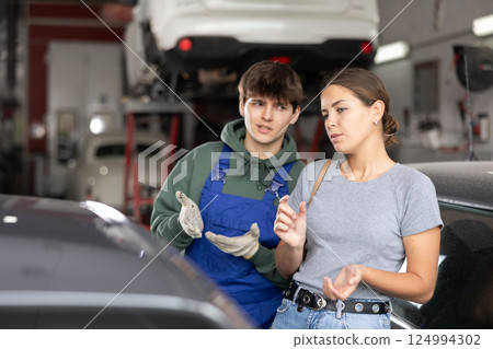 Guy car repair shop worker consulting woman client 124994302