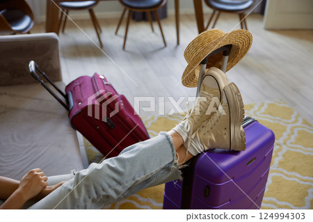 Cropped shot of female traveler legs in boots on luggage suitcase 124994303