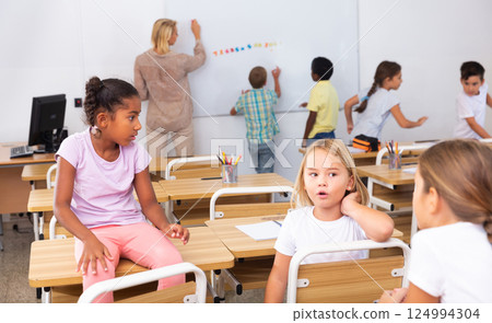 Girl and boy are sitting at the desk and talking about life in classroom 124994304