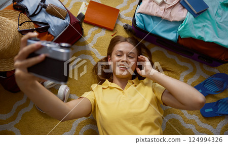 Young happy woman taking memory picture packing luggage for trip Young happy woman taking memory picture packing luggage for trip 124994326