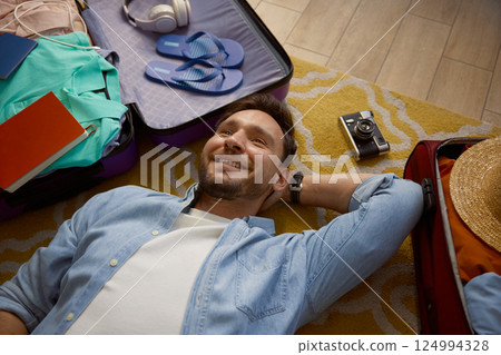 Young man lying on floor dreaming about future vacation trip Young man lying on floor dreaming about future vacation trip 124994328