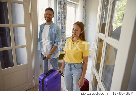 Young man and woman couple leaving home with packed travel suitcase 124994397