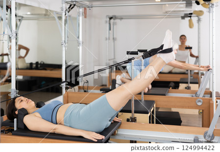 Young asian girl performing pilates exercises on reformer 124994422