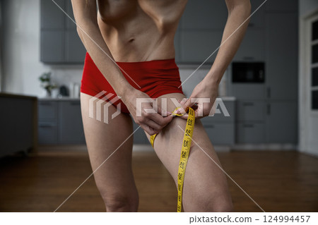 Cropped shot of unrecognizable anorexic woman measuring leg with tape 124994457