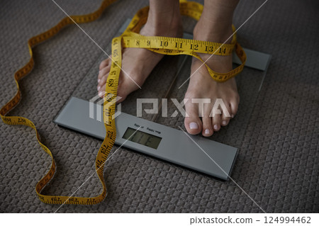 Unrecognizable woman standing on floor scales displaying low weight 124994462
