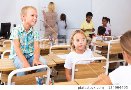 Cheerful preteen classmates talking at recess between lessons Cheerful preteen classmates talking at recess between lessons 124994495