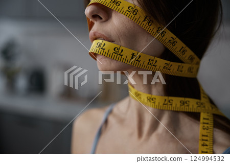 Woman face wrapped with measuring tape cropped closeup side view Woman face wrapped with measuring tape cropped closeup side view 124994532