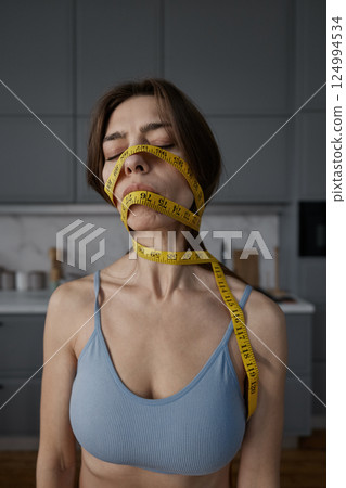 Woman face wrapped with measuring tape cropped closeup side view Woman face wrapped with measuring tape cropped closeup side view 124994534