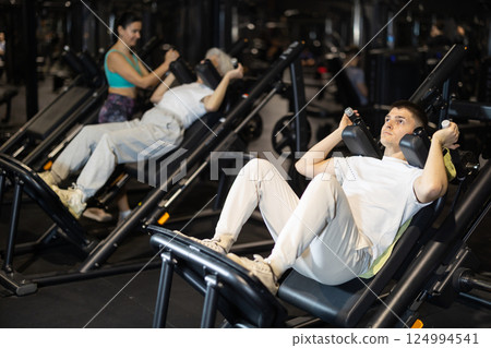 Guy using hack squat machine in modern gym 124994541