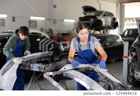 Young female mechanic polishes car with sponge Young female mechanic polishes car with sponge 124994618