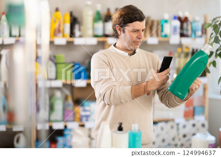 Man uses barcode to get information about liquid detergent in mobile application. Man uses barcode to get information about liquid detergent in mobile application. 124994637