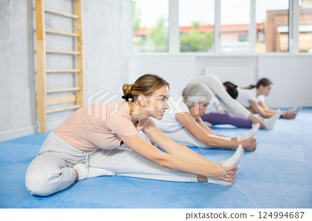 Group of women of different ages doing stretching before self defence training in gym Group of women of different ages doing stretching before self defence training in gym 124994687