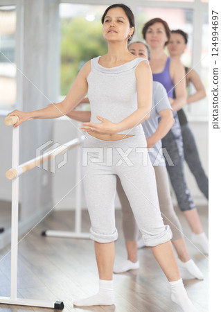 Woman practicing battement tendu during ballet group class for beginners Woman practicing battement tendu during ballet group class for beginners 124994697