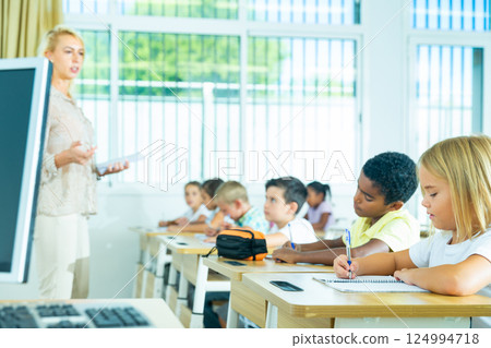 Focused preteen pupils studying in classroom with female teacher 124994718