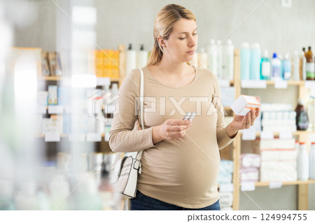 Pregnant woman chooses pills at pharmacy 124994755