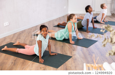 In studio with group of friends African girl stand perform dog muzzle up, Urdhva Mukha Shvanasana In studio with group of friends African girl stand perform dog muzzle up, Urdhva Mukha Shvanasana 124994920