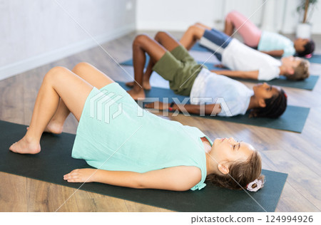In sport studio with group of friends, girl perform bridge pose, setu bandha sarvangasana 124994926