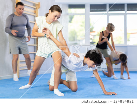Girls and boys learns to do power grip with trainer during a self-defense lesson in gym 124994981