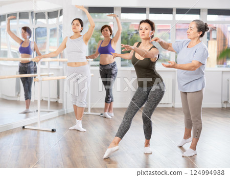 Senior ballet instructor correcting female beginne pose Senior ballet instructor correcting female beginne pose 124994988