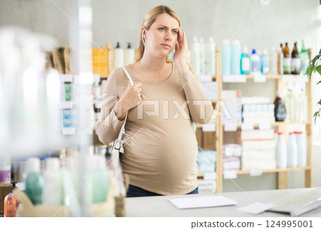 Pregnant woman having headache in drugstore 124995001