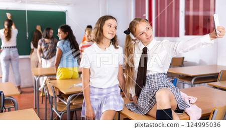 Two girls taking selfies in classroom during recess 124995036