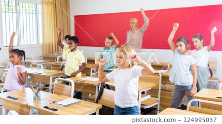 Preteen pupils doing warm-up in class with teacher at lesson 124995037