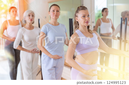Slender women practicing ballet at ballet barre 124995123
