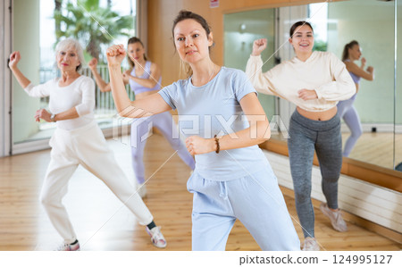 Active middle-aged woman practicing aerobic dance in training hall Active middle-aged woman practicing aerobic dance in training hall 124995127