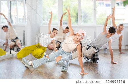 Group of teenagers in stylish clothes are training to dance low break and hip-hop in studio Group of teenagers in stylish clothes are training to dance low break and hip-hop in studio 124995136