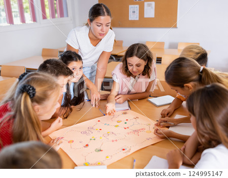 Teacher and schoolchildren play table game in school class 124995147