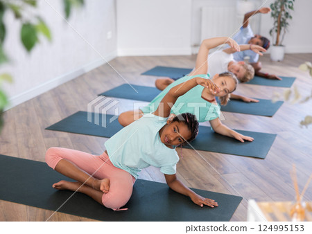 Training yoga kids on yoga mat in gym. 124995153