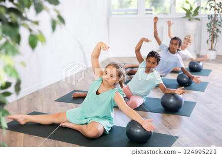 Kids doing pilates with softball. 124995221
