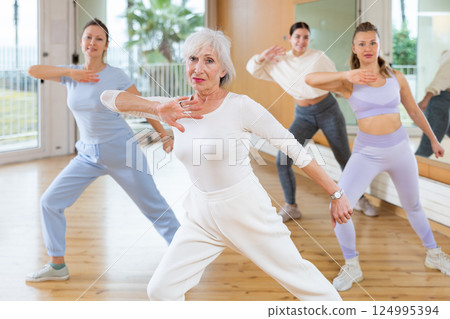 Dynamic elderly woman practicing aerobic dance in training hall Dynamic elderly woman practicing aerobic dance in training hall 124995394