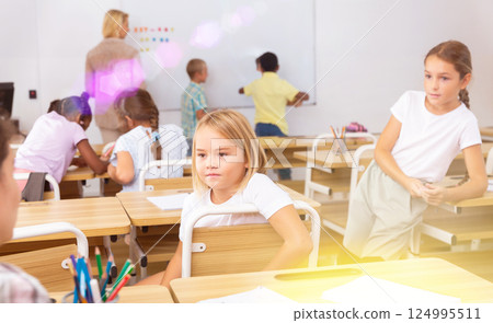 Girl and boy are sitting at the desk and talking about life in classroom Girl and boy are sitting at the desk and talking about life in classroom 124995511