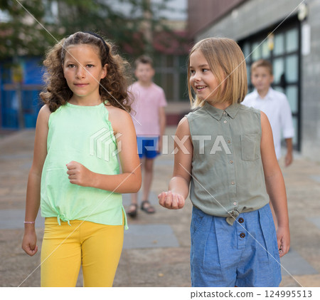 Friendly preteen girls talking during walk along city street 124995513