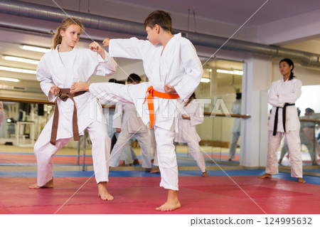 Young girl and boy in kimono training kicks Young girl and boy in kimono training kicks 124995632