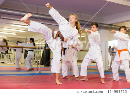 Serious girl practicing taekwondo movements in gym Serious girl practicing taekwondo movements in gym 124995713