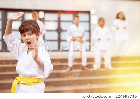 Boy in kimono doing karate moves in foreground Boy in kimono doing karate moves in foreground 124995730