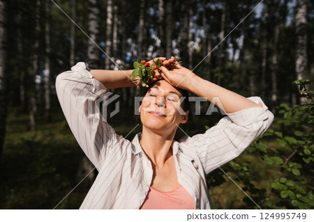 Woman enjoying healthy lifestyle and eco living in forest holding wild berries. Concept of freedom, calmness and nature connection 124995749
