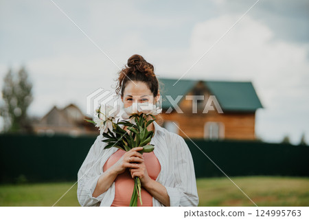 Female standing with flowers in backyard of countryside house on sunny summer day. Woman enjoying slow life, nature, and harmony in rustic environment Female standing with flowers in backyard of countryside house on sunny summer day. Woman enjoying slow life, nature, and harmony in rustic environment 124995763