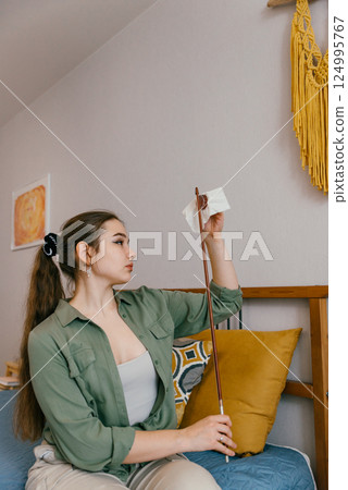 Focused young woman applying rosin to a bow as part of instrument preparation. A professional musician prepares her bow for rehearsal by fine-tuning its grip and response 124995767