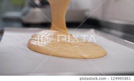 Pastry chef spreads batter on baking sheet parchment. Woman making sponge cake. 124995861
