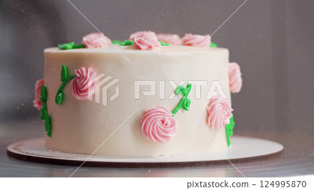 Elegant cake on turntable.Pink buttercream flowers on frosting. Bakery, pastry 124995870